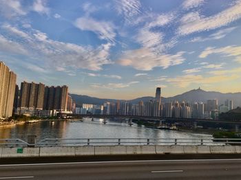 City by river and buildings against sky