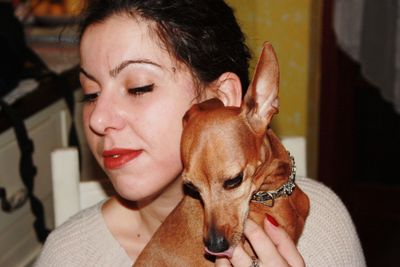 Close-up of woman holding dog sitting at home