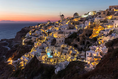High angle view of illuminated cityscape by sea against sky