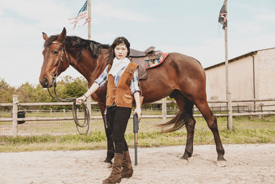 Portrait of woman standing with horse at ranch