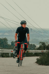 Rear view of man riding bicycle on road