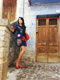 Full length of fashionable woman standing against house