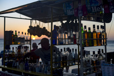 Rear view of man in glass at city during sunset