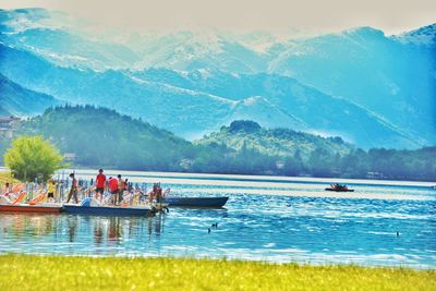 People enjoying in lake against mountains