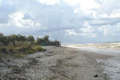 Scenic view of beach against cloudy sky