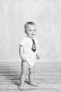 Cute boy looking away while standing against wall