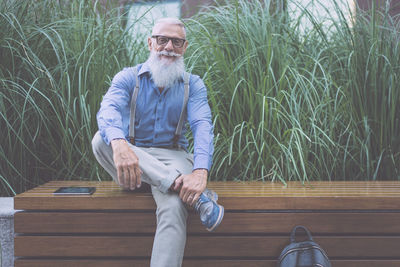 Senior hipster sitting against plants