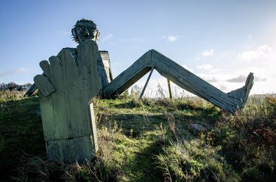 Old sculpture on field against sky