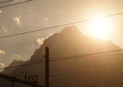 Low angle view of electricity pylon against cloudy sky