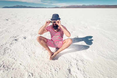 Full length of man relaxing on sand at beach