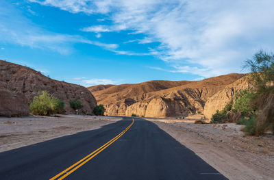 Road by mountains against sky