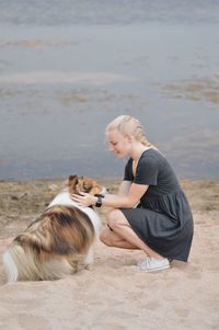 Side view of a dog and young woman on beach