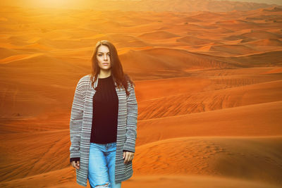 Portrait of young woman standing in desert during sunset