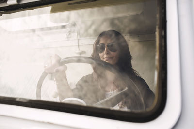 Businesswoman wearing sunglasses while driving portable office truck