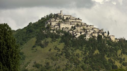 Buildings and trees on hill against sky