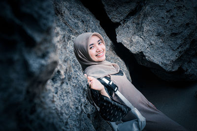 Portrait of smiling young woman standing on rock