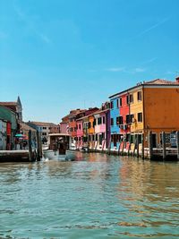 View of canal by buildings against blue sky