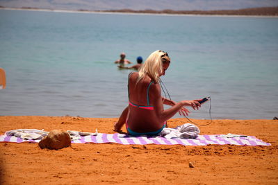 Woman listening music while sitting at beach