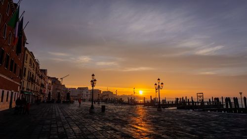 Street amidst buildings against sky during sunset