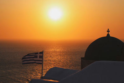 Silhouette cross against sea during sunset