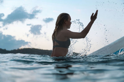 Female surfer in the ocean at sunset