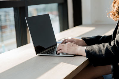 Side view of woman using laptop on table