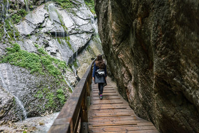 Woman standing on footpath amidst rocks