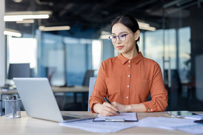 Portrait of young man using laptop at office