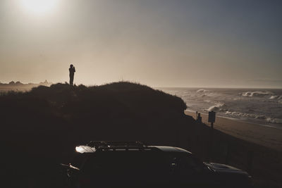 Silhouette people on beach by sea against sky