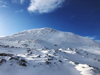 Low angle view of snowcapped mountains against blue sky