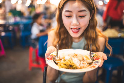 Smiling young woman holding food in plate