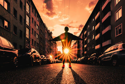 Rear view of man on street against sky at sunset