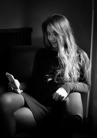 Woman using mobile phone while sitting at home