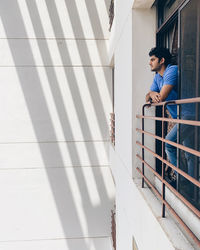 Young man on railing against wall