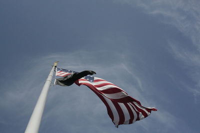 Low angle view of flag flying against sky
