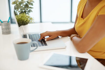 Midsection of woman using laptop at table