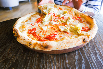 Female hand taking slice of hot vegitarian pizza. eating pizza at italian restaurant