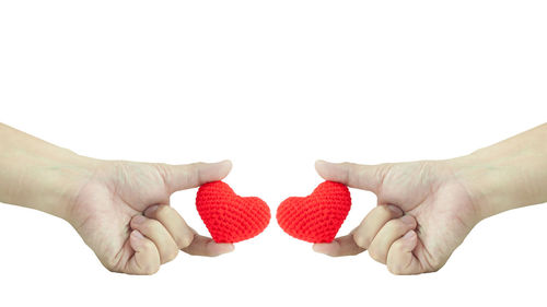 Close-up of hands holding heart shape over white background