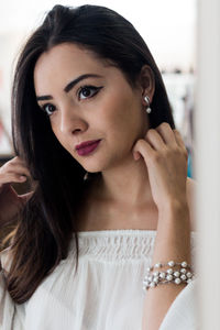 Close-up of young woman trying earring while standing in store