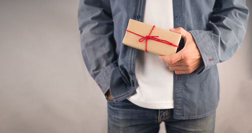 Midsection of man holding mobile phone in box