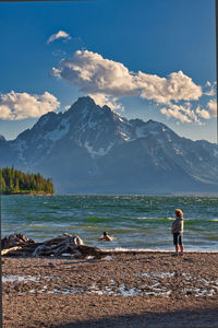 Woman standing by sea against sky