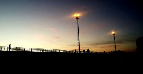 Low angle view of electricity pylon against sky at dusk