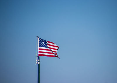 Low angle view of flag against clear blue sky