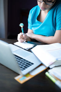 Midsection of woman using smart phone while sitting on table