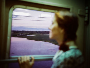 Rear view of woman looking through train window