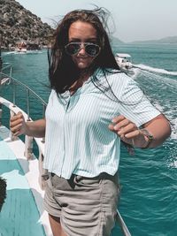 Woman wearing sunglasses standing by sea