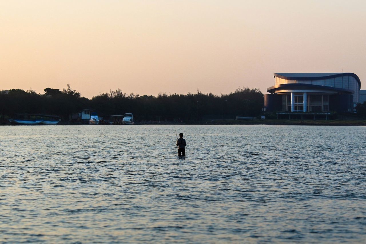 water, sky, waterfront, real people, architecture, built structure, nautical vessel, sunset, nature, mode of transportation, clear sky, one person, transportation, building exterior, silhouette, copy space, tree, scenics - nature, lake, outdoors