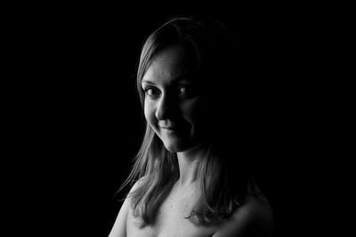 Portrait of young woman against black background