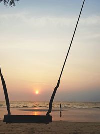 Silhouette people on beach against sky during sunset