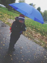 Man holding umbrella on wet street in rainy season